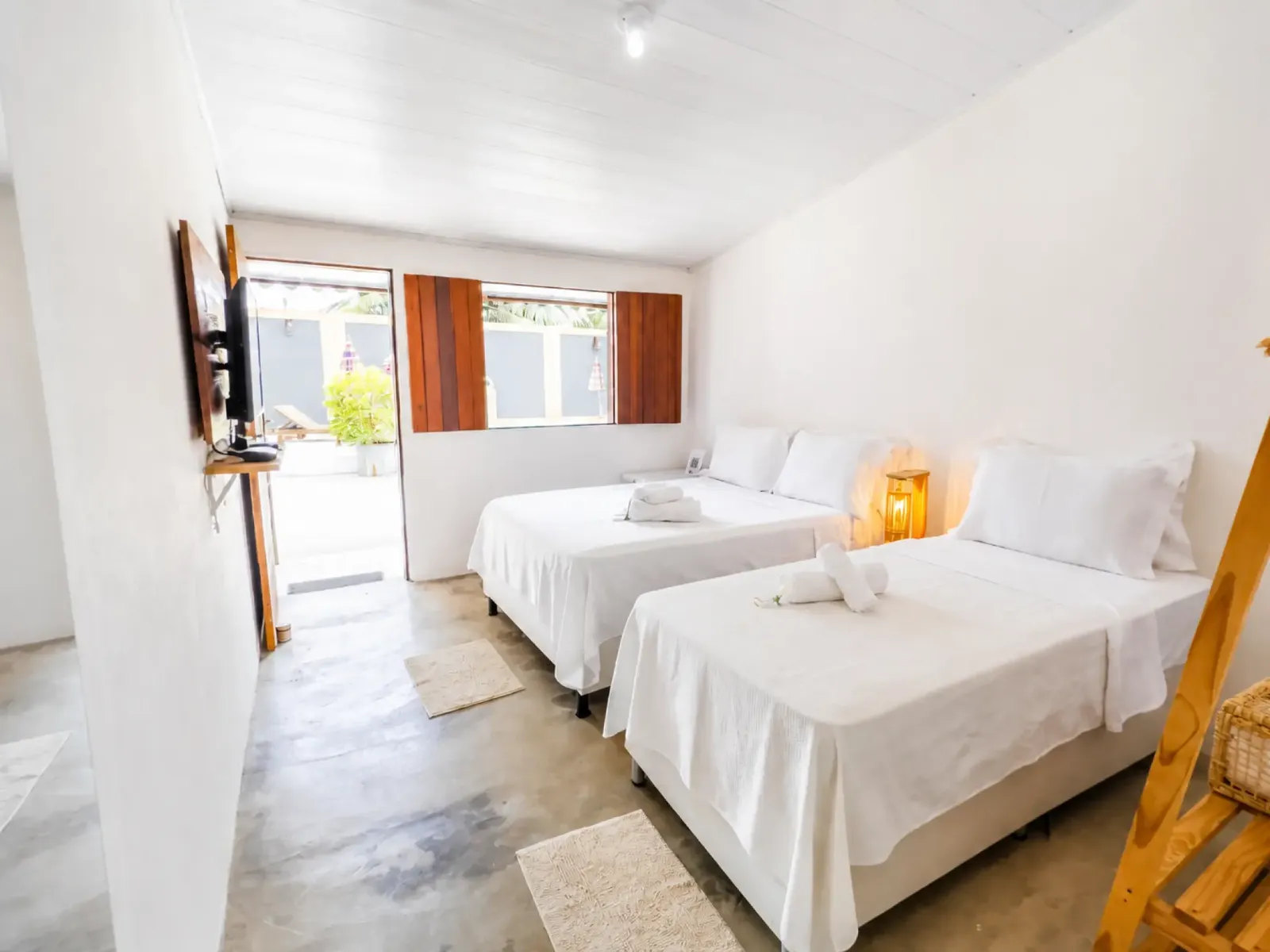 Guest room with two beds and a door opening straight onto the pool patio