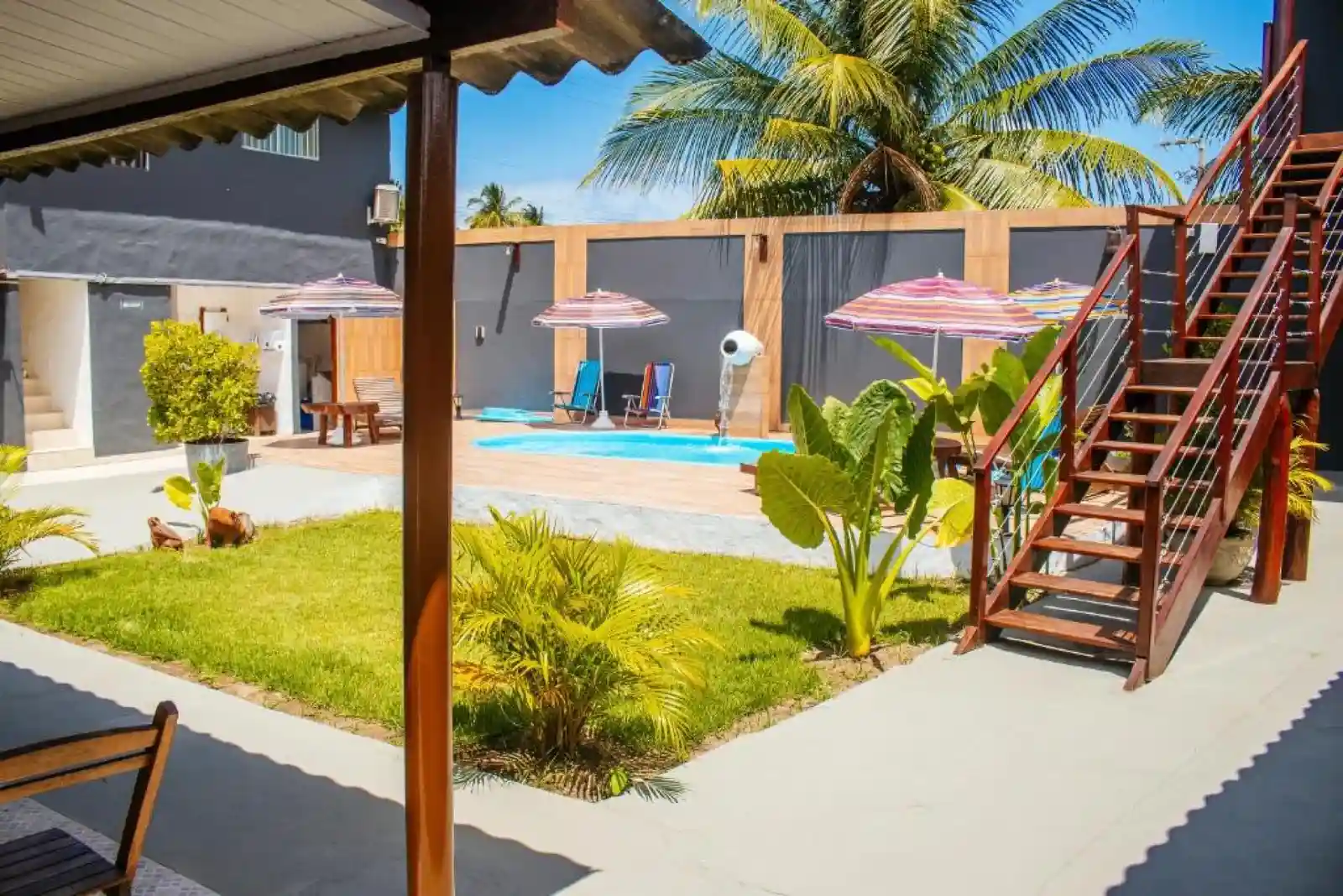 View across the lawn and pool deck to the guest rooms and wooden staircase