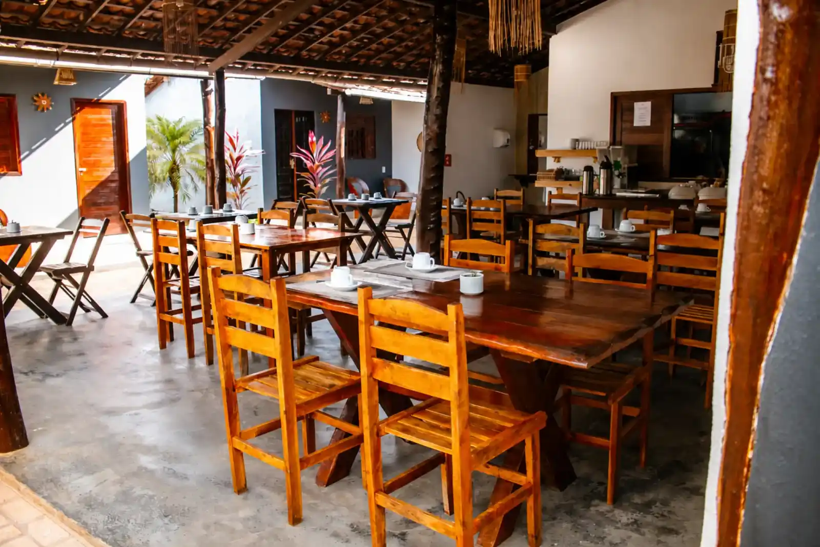 Covered breakfast area with wooden tables and chairs under a tiled roof